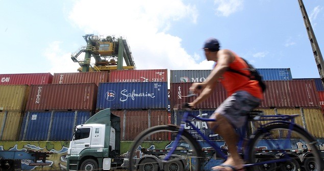 A dock worker rides his bicycle in front of containers at the port of Santos February 22, 2013. REUTERS/Paulo Whitaker