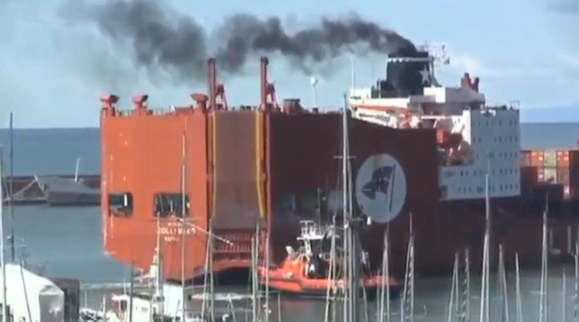 A tug assists the Jolly Nero in conducting the same maneauver